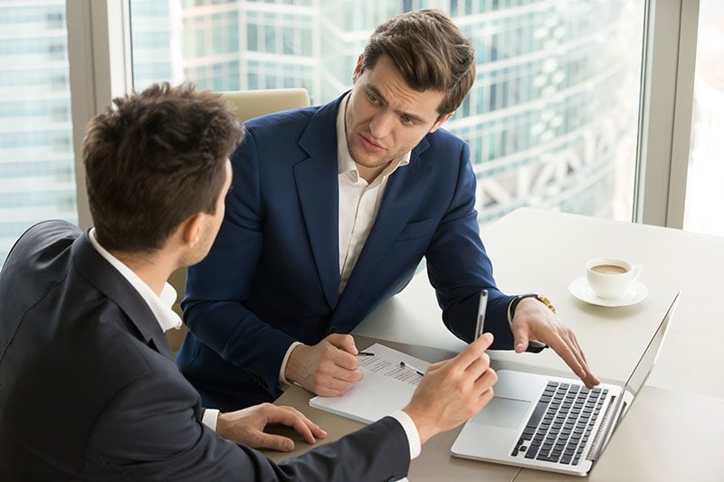 woman shaking hands with male sitting at desk