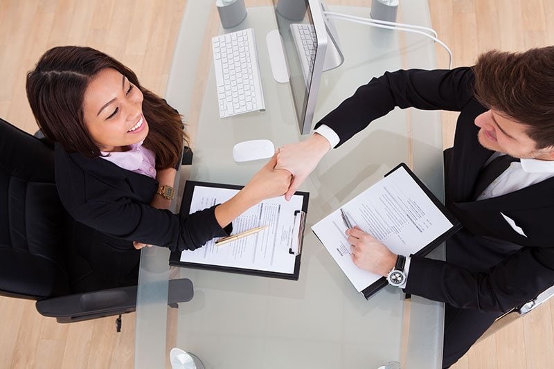 female and male shaking hands at desk